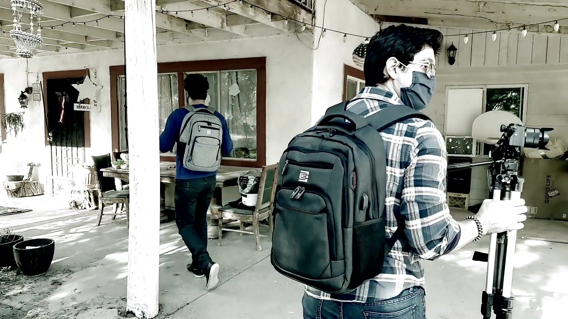 A man shares personal testimony in an intimate indoor setting while a film crew captures the footage on a residential porch. The sequence documents the intersection of reflective storytelling and technical production.