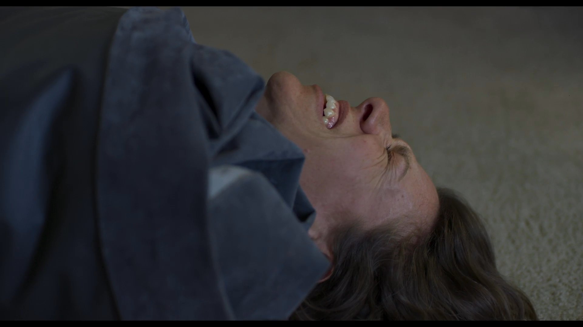 A woman lies on the ground in visible physical distress before transitioning to the interior of a vehicle, where she consumes medication to manage her condition.
