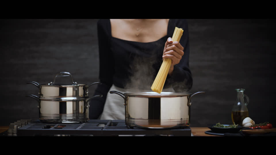 Film still: a cook lowering pasta into a steaming Lagostina pot