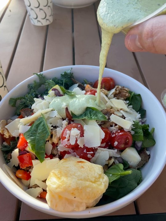 Aubergine Kitchen - Drizzling the sola Teo dressing on the tríptico salad - Mediterranean Near Me - Riverton, Utah