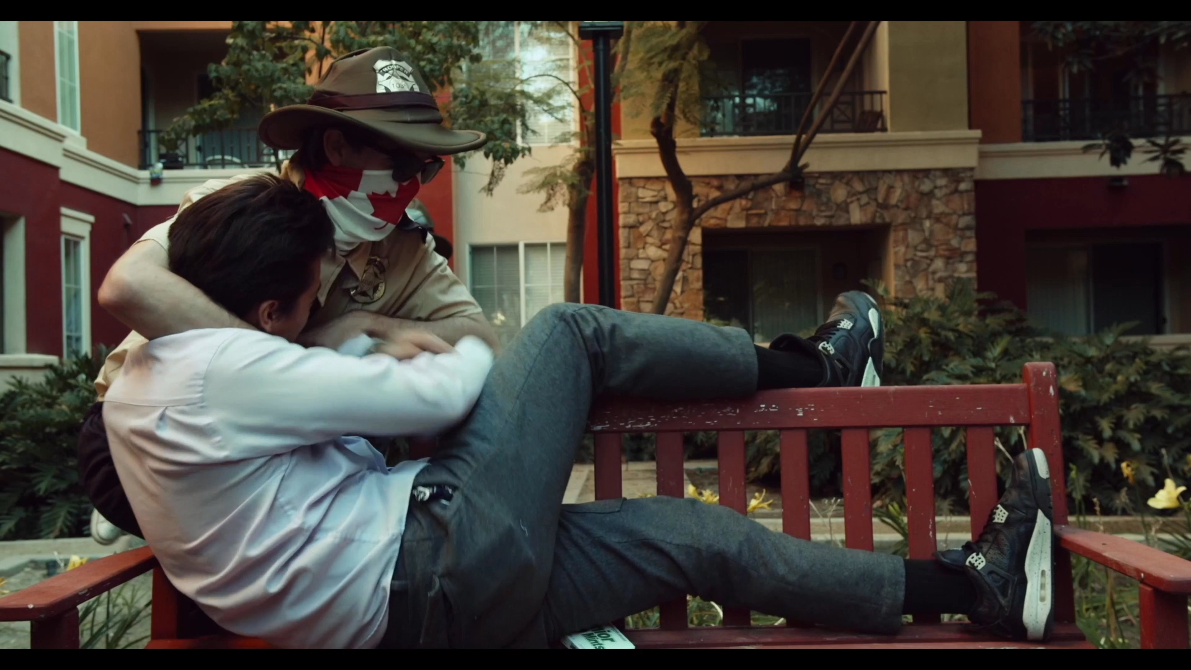 A man and a woman sitting on a park bench are suddenly accosted and physically attacked by an masked intruder. The violent altercation escalates rapidly before the scene shifts to the aftermath.