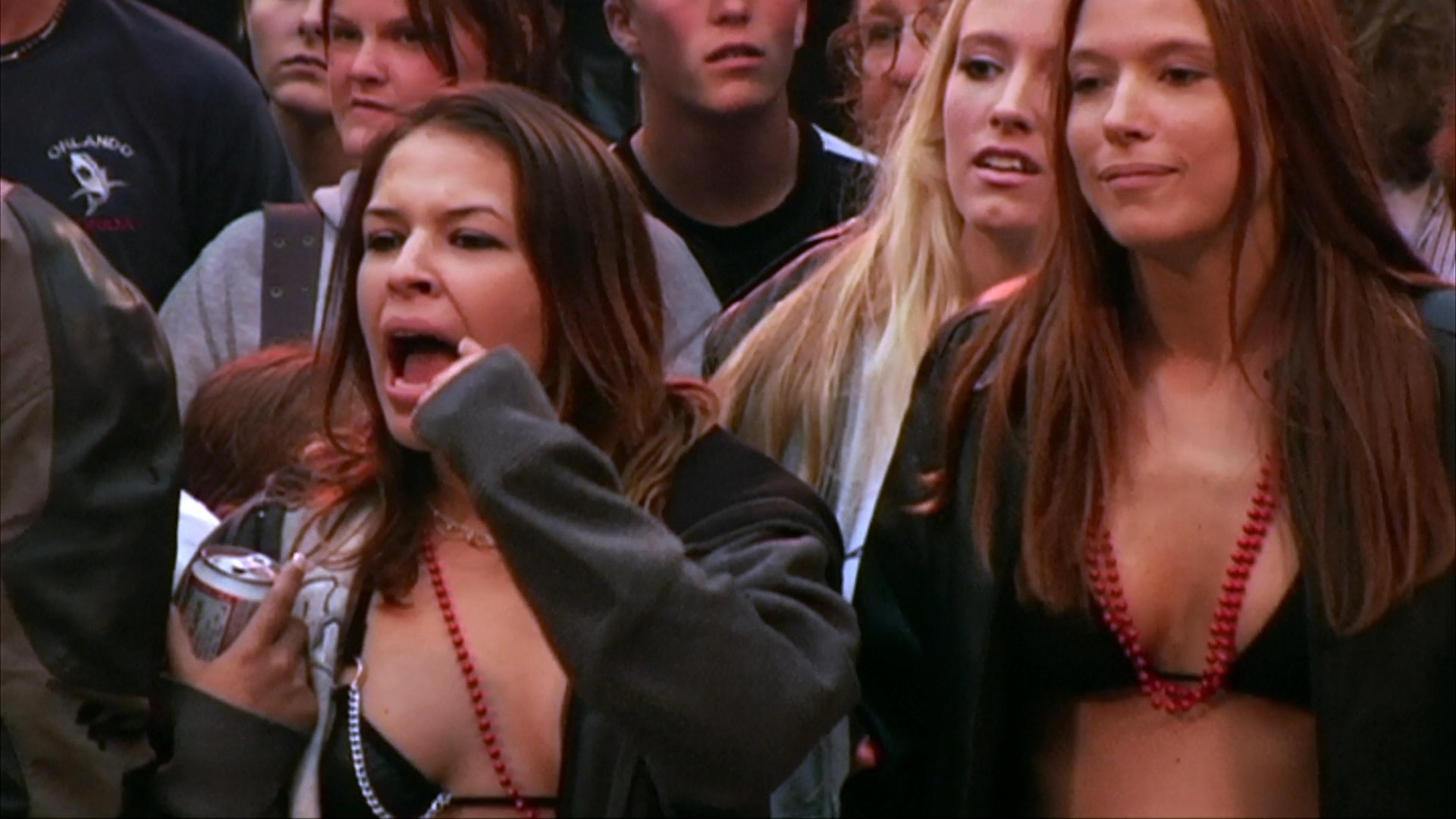 Two women engage in a physical fight inside a ring surrounded by a crowd of onlookers. The match quickly turns into a scramble as spectators intervene to separate the participants.