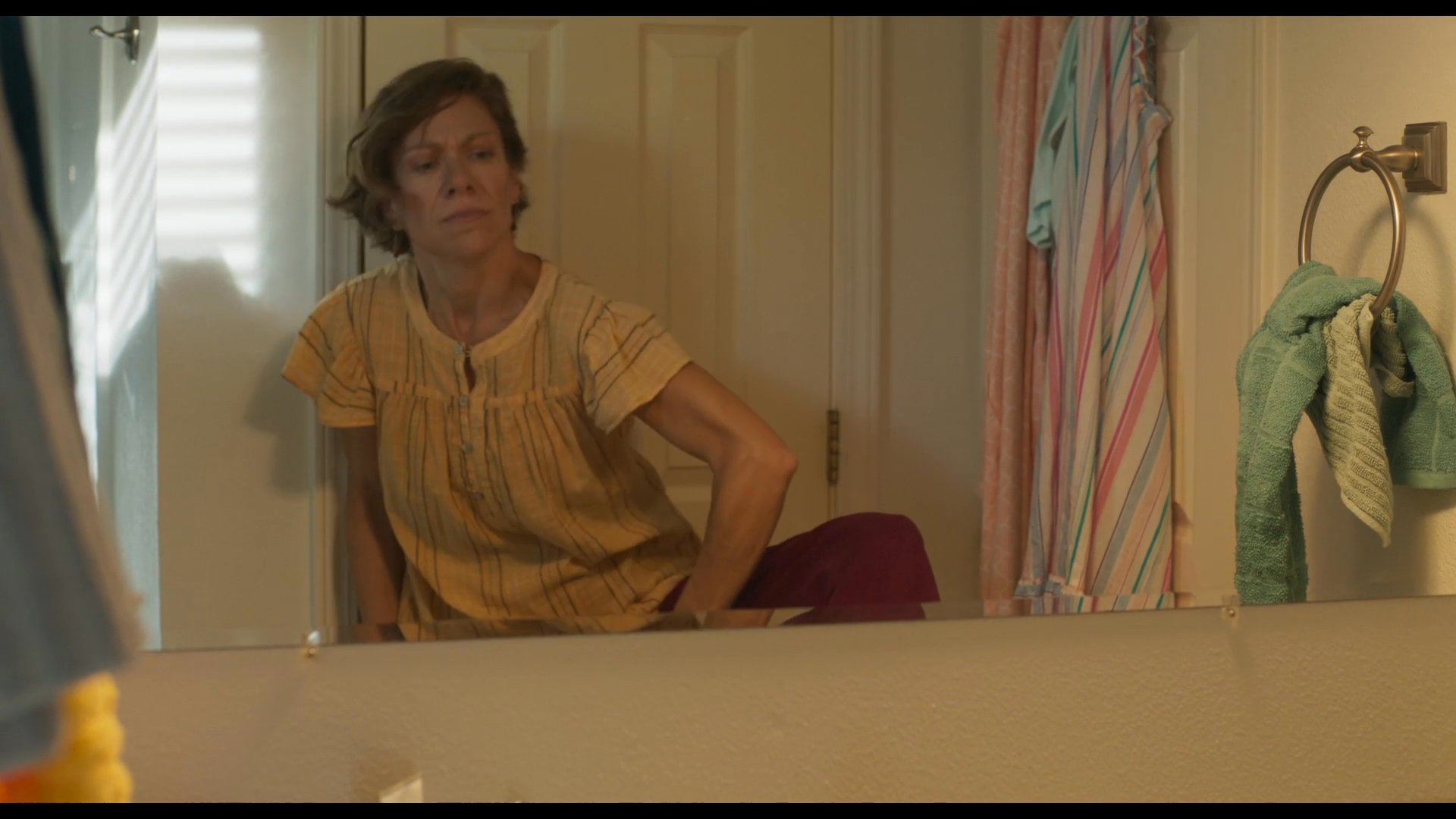 A woman prepares for her day in the bathroom using deodorant, followed by a young man discussing sports practice over a phone call while sitting in a car.