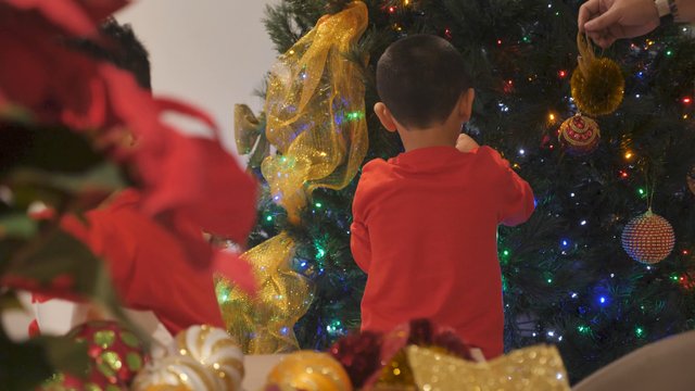 Boy hangs decorations on Christmas tree