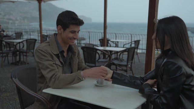 A loving couple playing a finger-wrestling game in a café