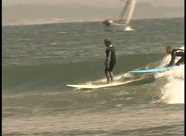 Surfers in wetsuits navigate ocean waves on surfboards while practicing various riding maneuvers.
