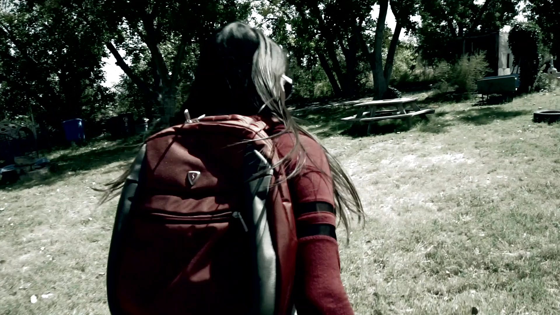 A man and a woman navigate a residential property with heightened caution and urgency. The sequence captures their reactive movements and quickened pace as they scout the surroundings.