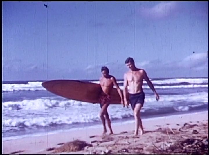 Athletic individuals prepare vintage surfboards near a parked automobile before transitioning to the water. The sequence concludes with a surfer skillfully riding a wave on a longboard.