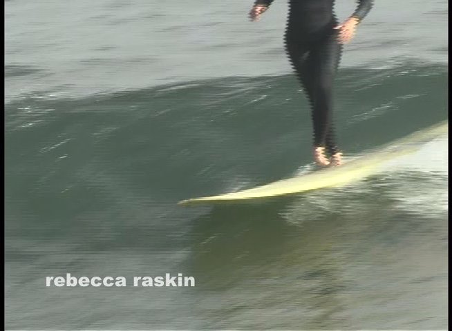 Surfers in wetsuits navigate waves on longboards in the ocean, demonstrating balancing and maneuvering techniques.
