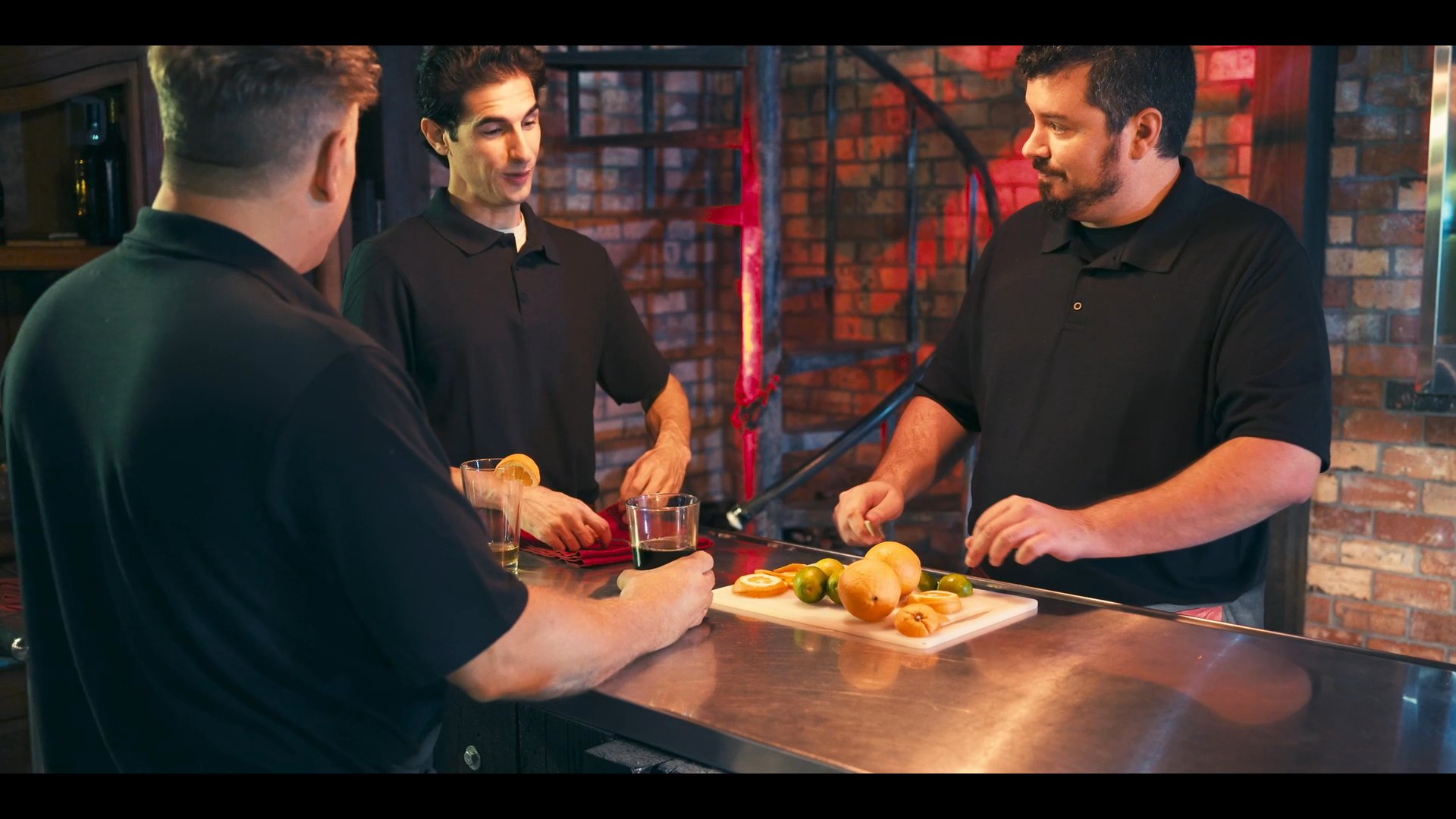 A professional bartender demonstrates proper drink preparation and garnishing techniques to staff within a brewery setting.