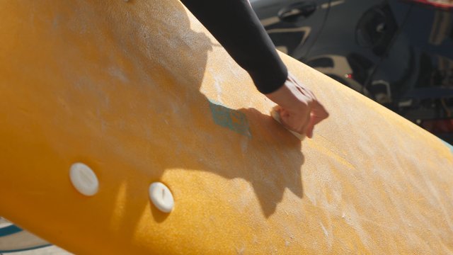 Rubbing wax on a surfboard