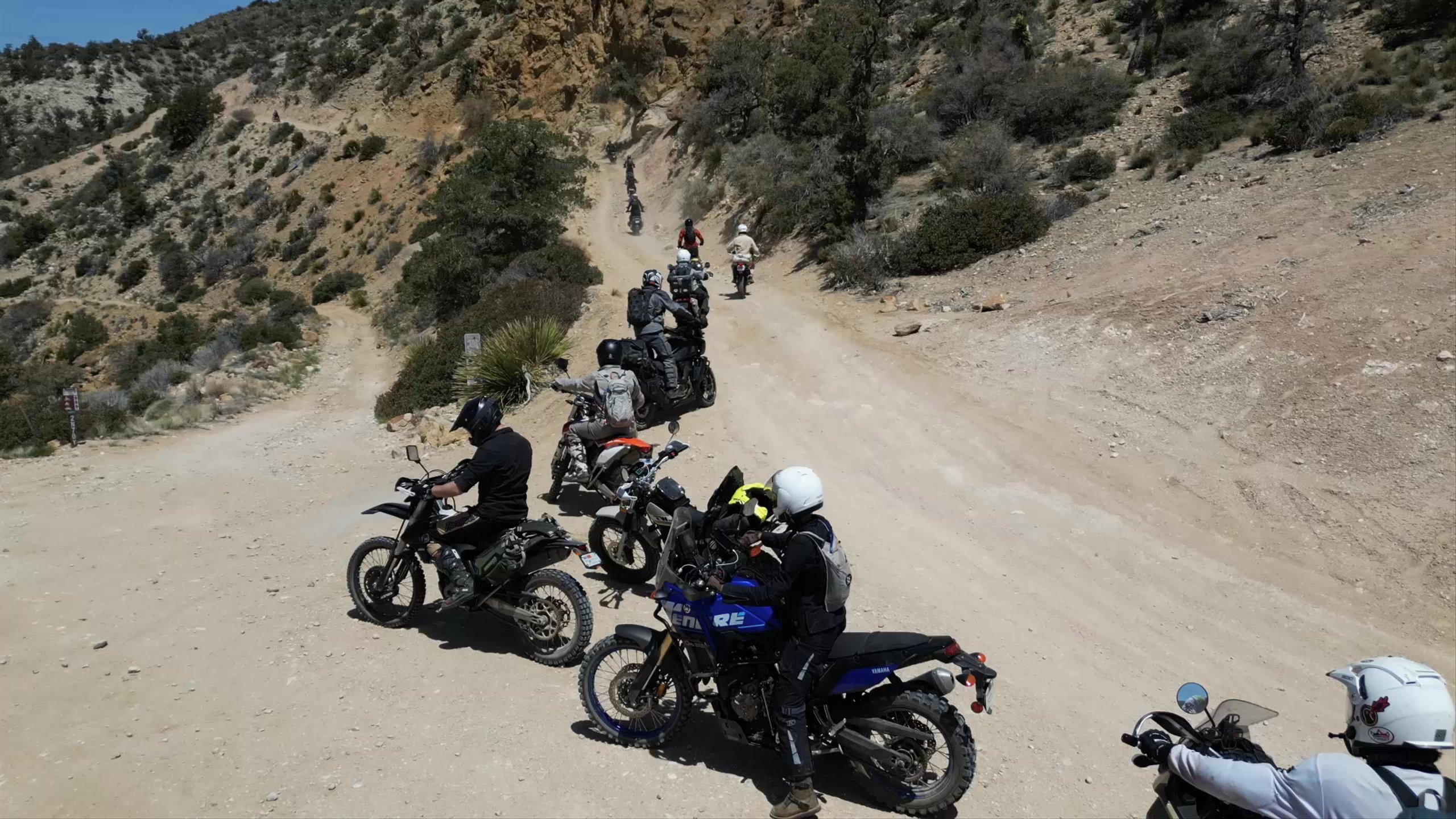 Drone view of motorcyclists riding through desert mountain path