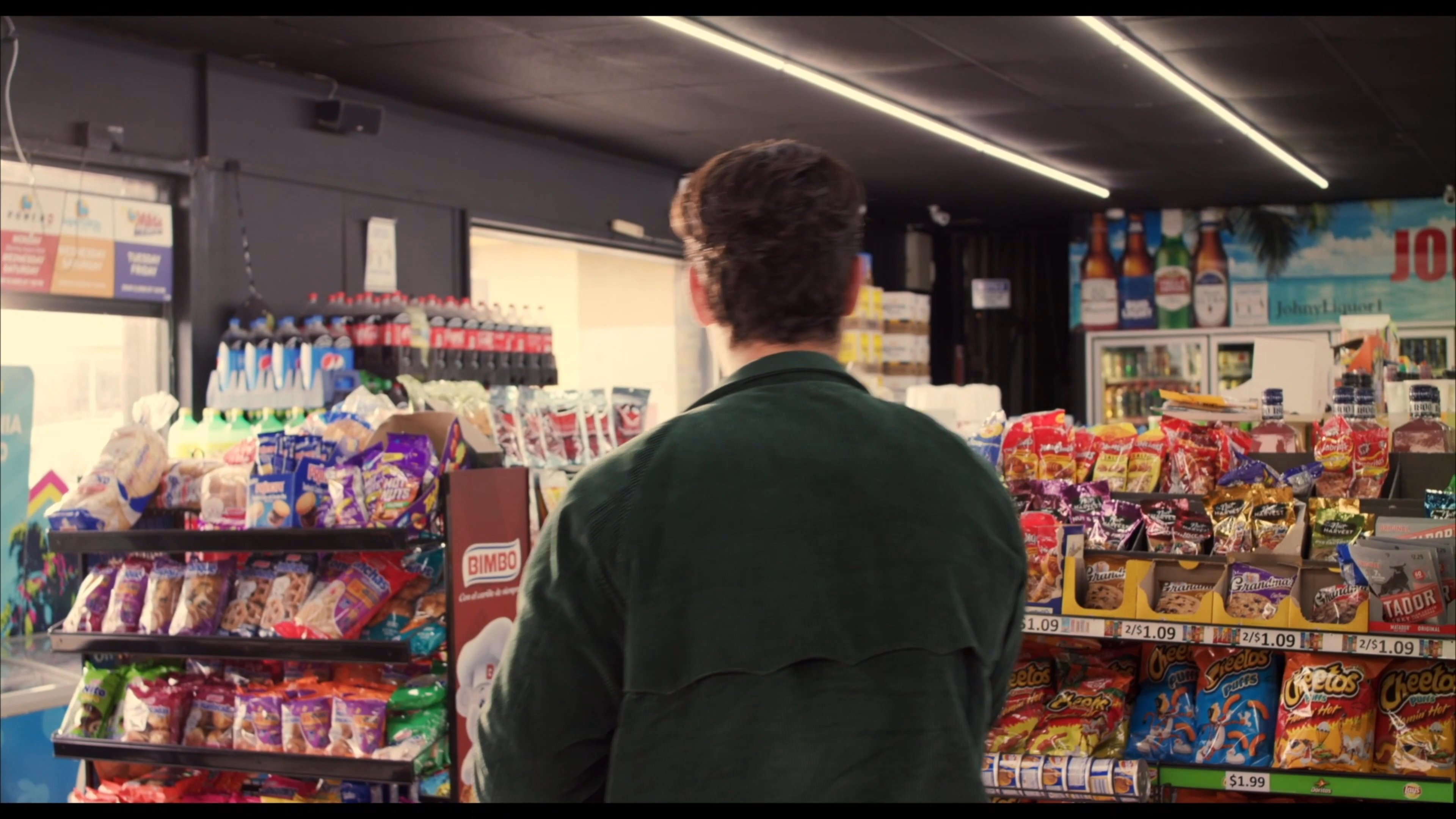 A man purchases a chocolate egg at a convenience store and shares it with a female employee, who then consumes it.