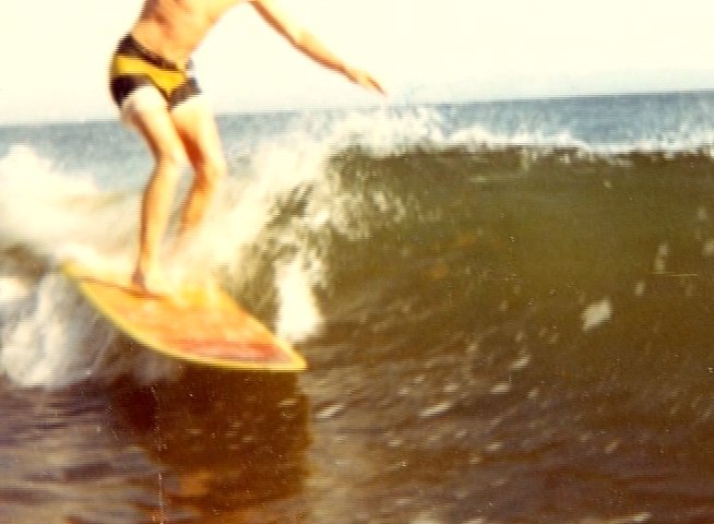 A surfer rides waves in the ocean, interspersed with archival text detailing White Owl Surfboards' craftsmanship and Santa Cruz location. The sequence concludes with a scenic shot of a beach street sign near the coast.