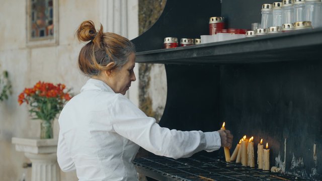 A religious woman lights a candle