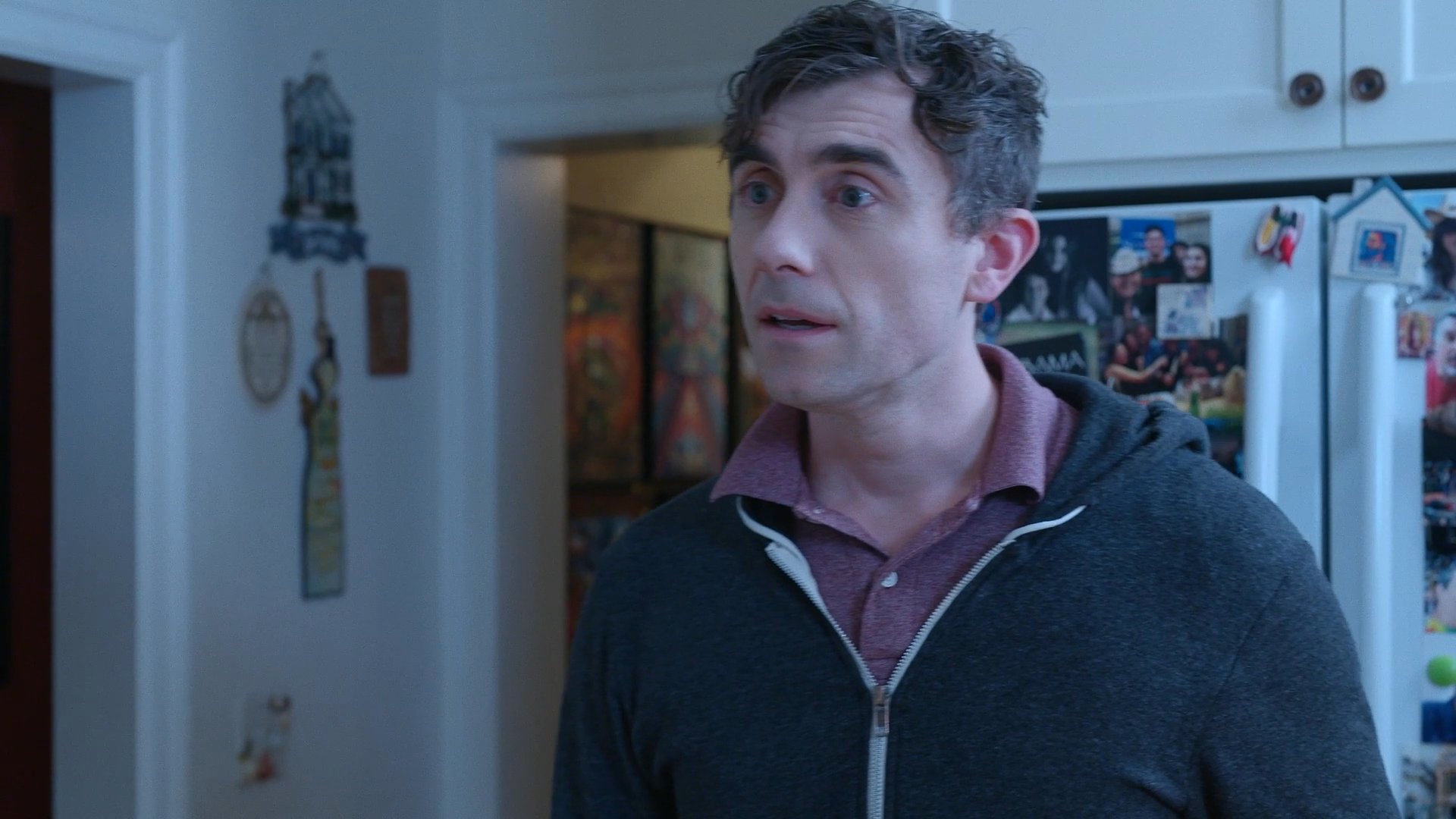 A man and an older woman engage in a tense, emotionally charged conversation within a kitchen setting, culminating in the man displaying signs of significant distress.