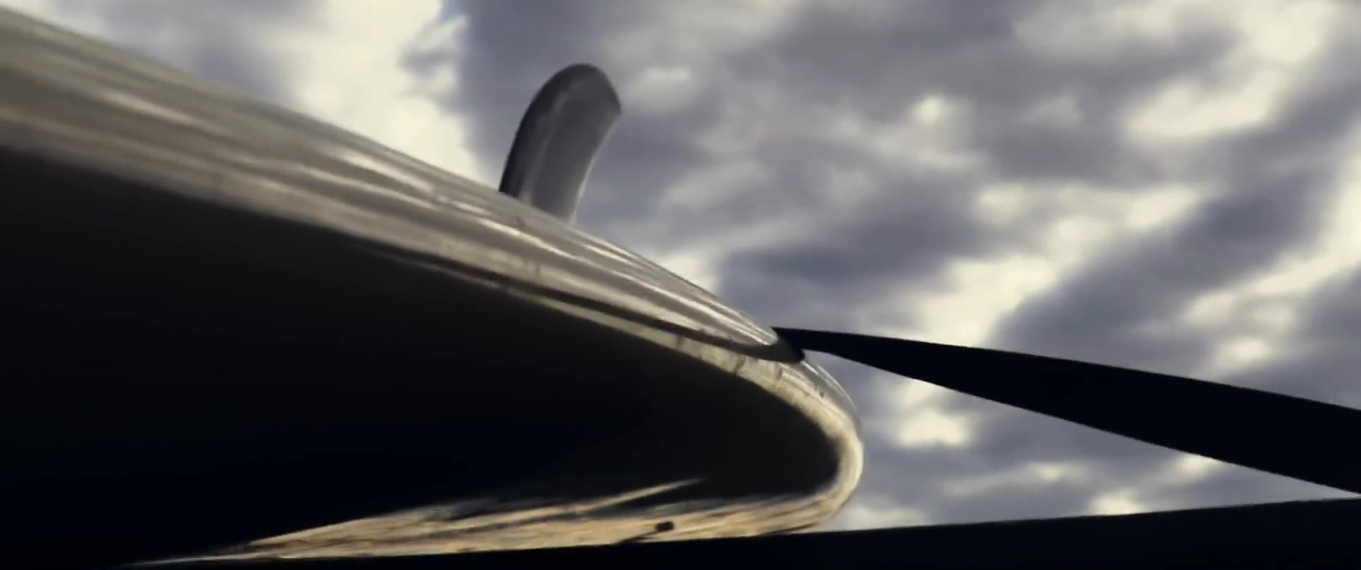 A man in sunglasses drives a classic blue pickup truck along a desert road, transitioning to an aerial perspective of the vehicle and a nearby aircraft propeller against a cloudy sky.