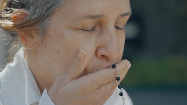 A woman kisses rosary beads