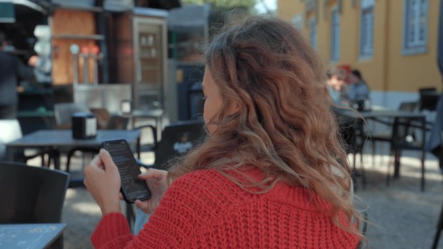 A girl using her smartphone while sitting at a café