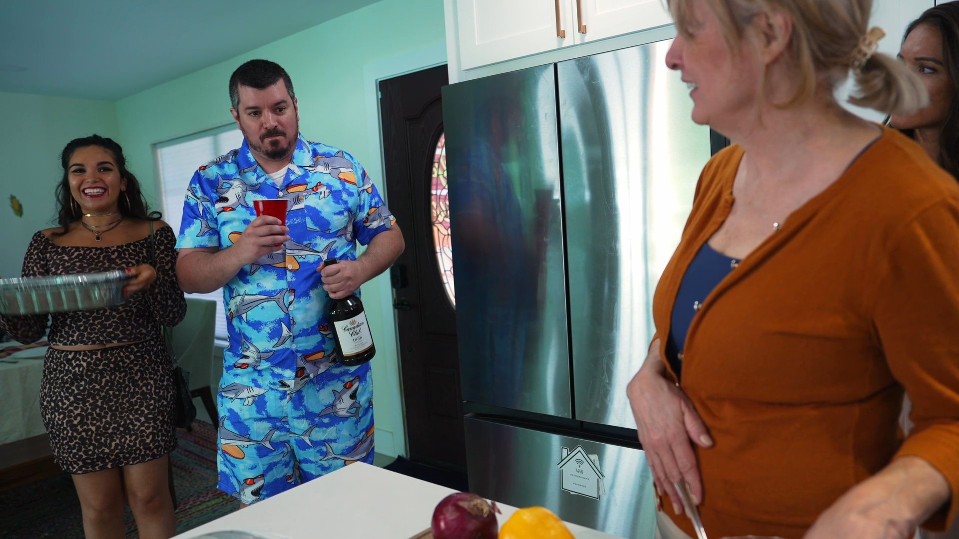 Friends gather in a home kitchen for a holiday party, where conversations and drinks eventually transition into a more somber, reflective mood.