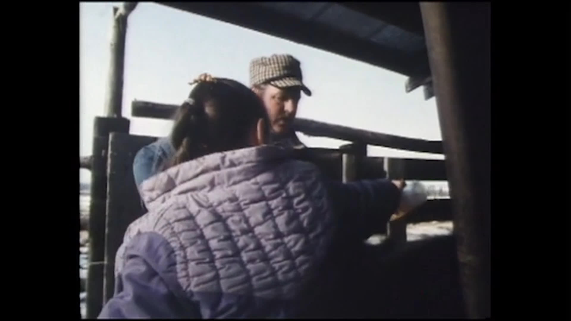 A mother shares a quiet moment with two girls outdoors before the family gathers by a livestock pen. A man tends the fence as a cow moves into view, while the mother reflects on letting her daughters enjoy being children.