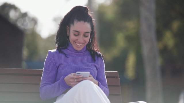 Woman texting on a park bench